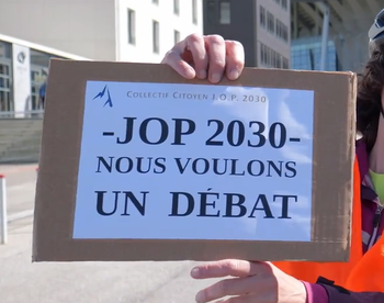 Pancarte du Collectif Citoyen JOP 2030 "JOP 2030 - Nous voulons un d&eacute;bat" devant les locaux du COJOP &agrave; Lyon le 16/05/2025 Stadiaum &agrave; Lyon, lors de la V&eacute;lo-COJOP du 16052025